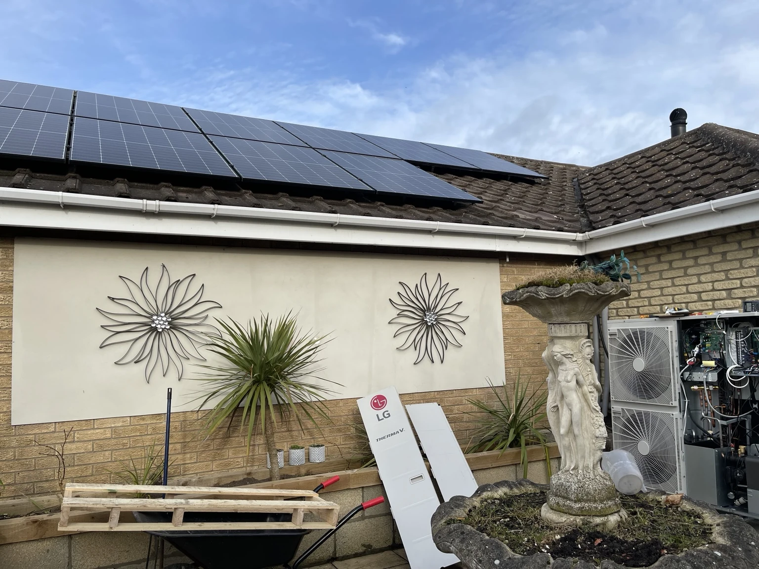 Rooftop solar panels and an LG heat pump with its service cover removed during installation